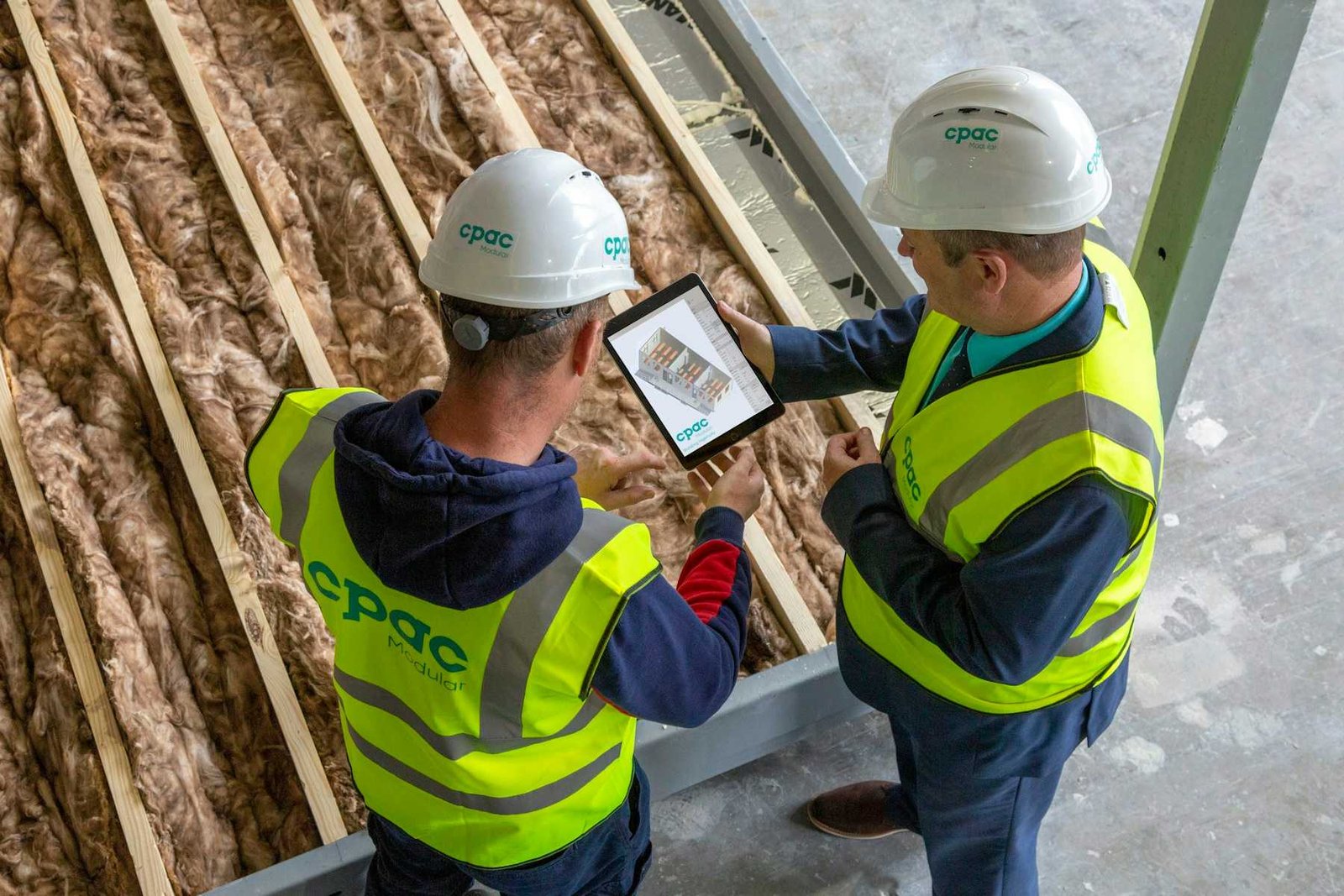 Deux professionnels contrôlent l’isolant posé entre les chevrons d’une toiture